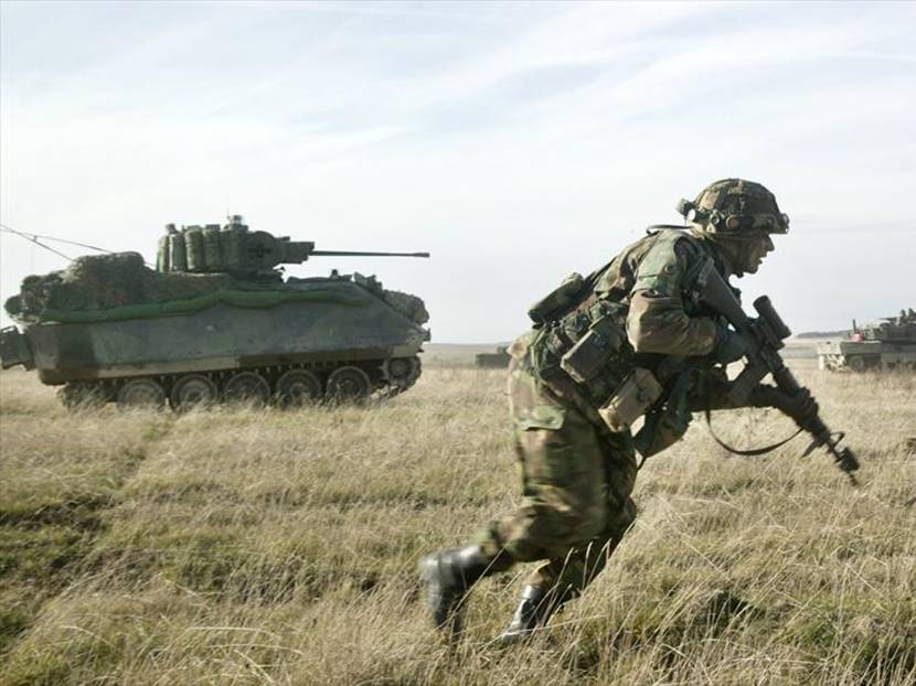 Militair tijdens een oefening met op de achtergrond een CV90. Archieffoto: ministerie van Defensie.