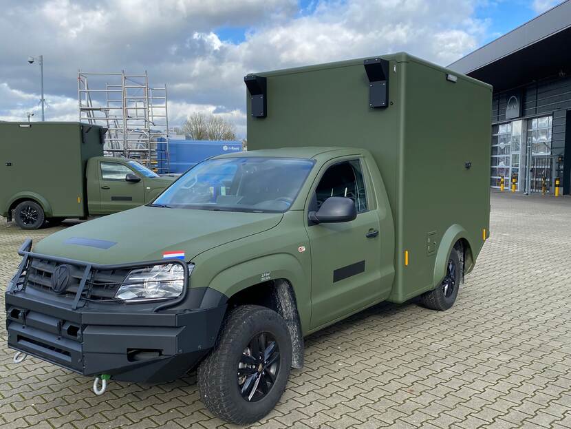 Groen militair voertuig de Volkswagen Amarok met een opbouw achterop het voertuig geparkeerd.