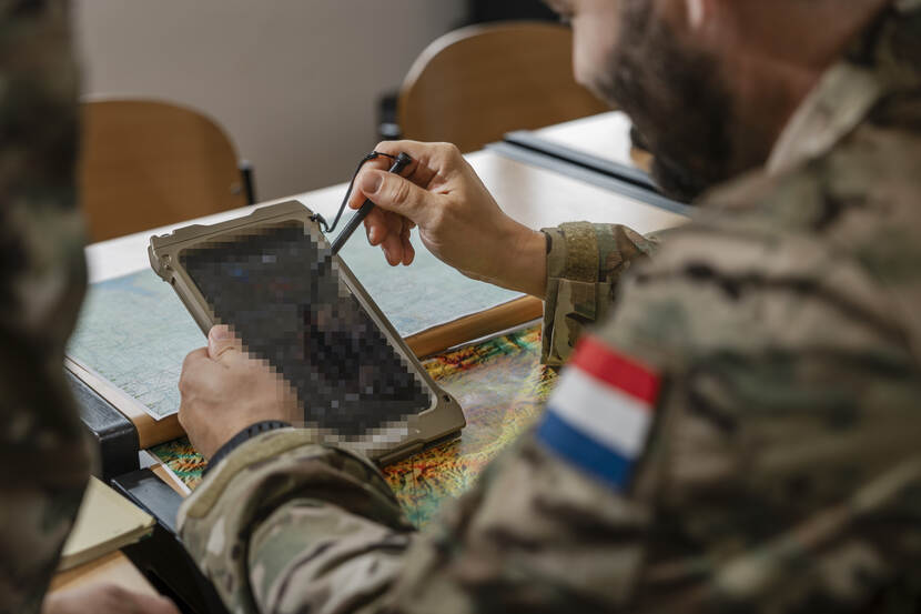 Een militair kijkt op iets wat lijkt op een grote mobiele telefoon.