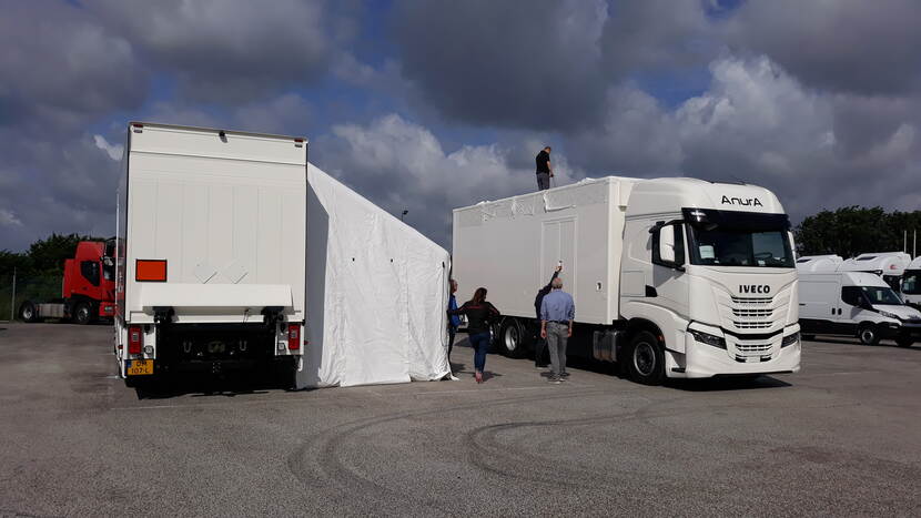 Op een parkeerplaats zetten Defensiemedewerkers de opblaasbare zijtenten van de duiktrucks op.