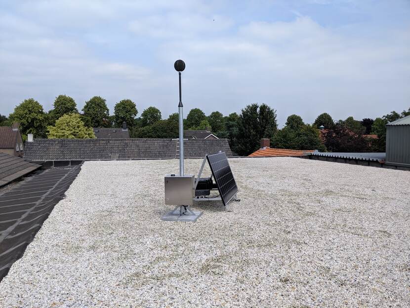 Een geluidsniveaumeter opgesteld op het dak van een gebouw.