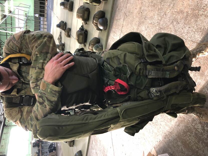 Militair met aflaatsysteem in een hangar met parachutes.