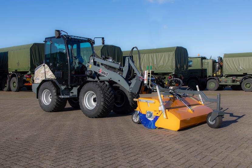 Wiellaadschop met een opzetborstel op een parkeerplaats met aanhangwagens.