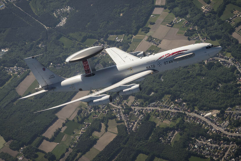 AWACS-vliegtuig met 'tiger'-beschildering boven bewoond gebied.