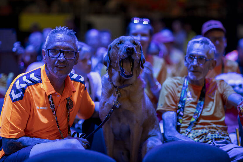 Twee Nederlandse sporters zitten met in het midden een hond.