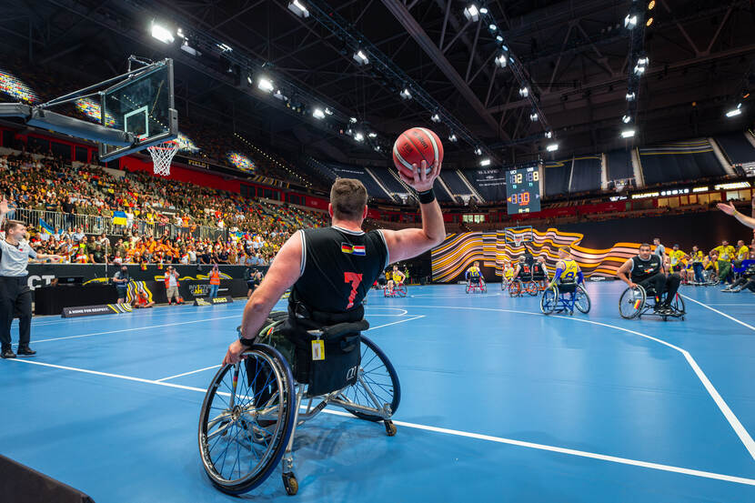 Een Nederlandse rolstoelbasketballer gooit de bal.