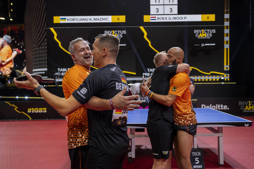 4 tafeltennisspelers omhelzen elkaar.