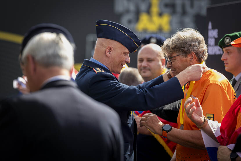 Een man krijgt een medaille om zijn nek.