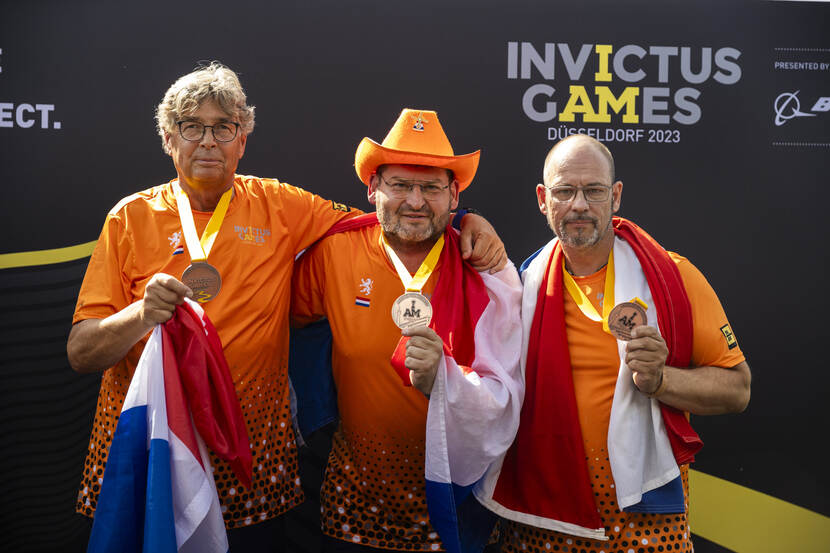 3 Nederlandse sporters laten hun medaille zien.