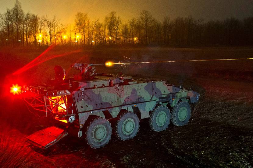 Browning M2 QCB machinegeweer op een Boxer-pantserwielvoertuig in het donker. Goed zichtbaar is de lichtspoormunitie.