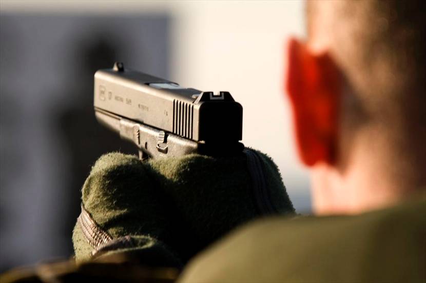 Militair van achteren gefotografeerd met eenGlock 17 Gen4, pistool 9mm in z'n handen.