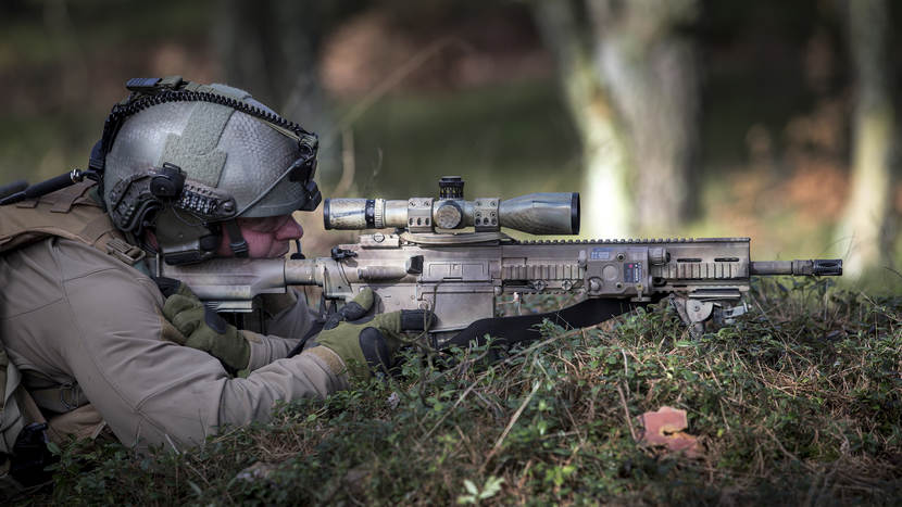 Een sniper ligt in het gras met een HK417-scherpschuttersgeweer.