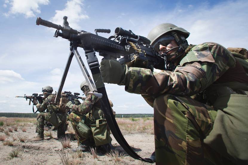 Infanterist met een een Minimi-licht machinegeweer. Naast hem zitten nog 2 infanteristen.