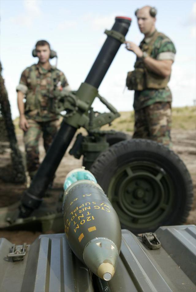 Een 120mm-mortiergranaat, op de achtergrond het mortier.