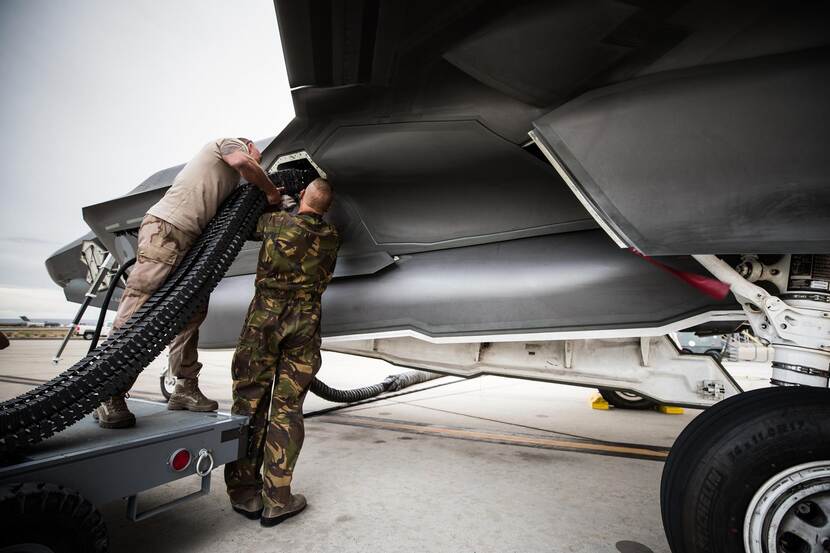 2 wapentechnici laden een kogelband met 25mm-patronen in een F-35.