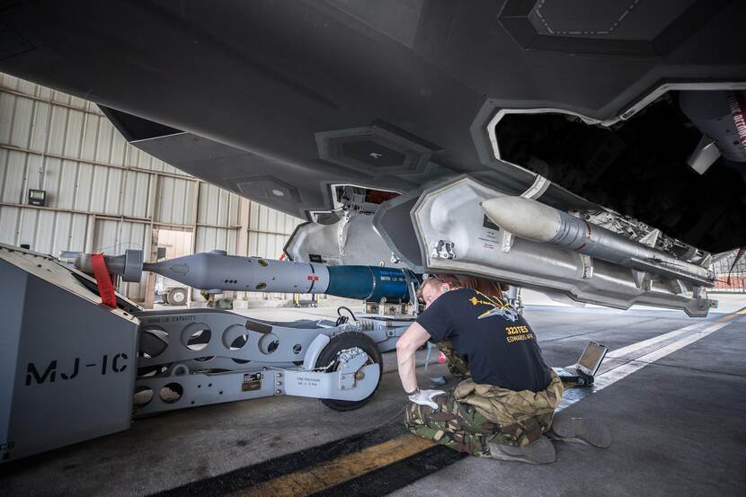 Een militair checkt onder een F-35 de AIM-120 Amraam-raket.