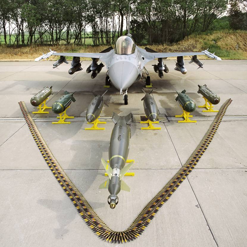 Een F-16 behangen met bommen en raketten en ervoor (lasergeleide) bommen en munitiebanden van het boordkanon uitgestald.