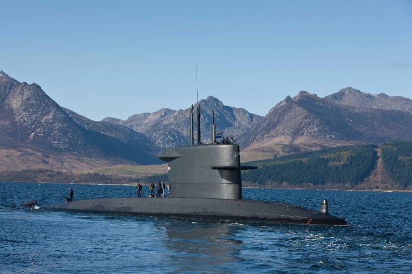 Onderzeeboot Zr.Ms. Bruinvis aan de oppervlakte, met bergen op de achtergrond.