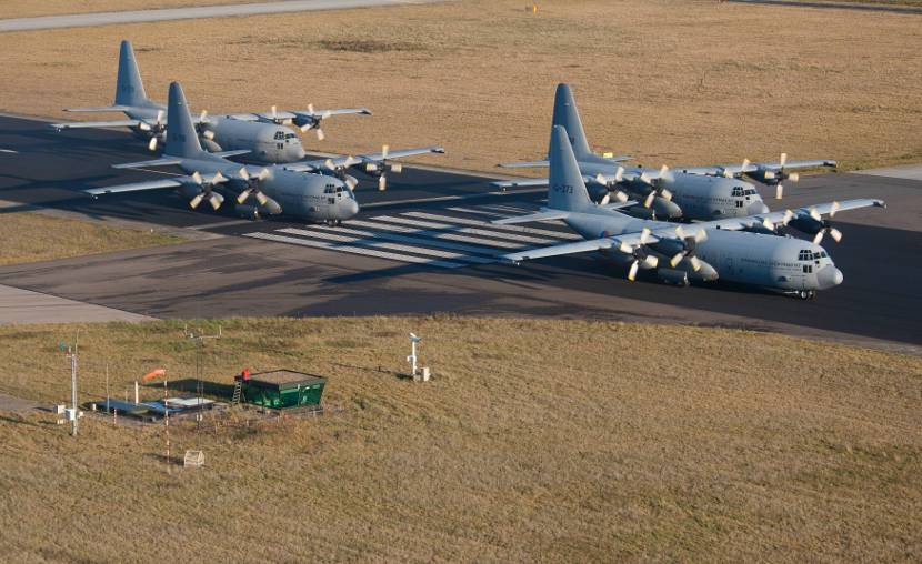 4 C-130 Hercules-transportvliegtuigen op een vliegbasis.