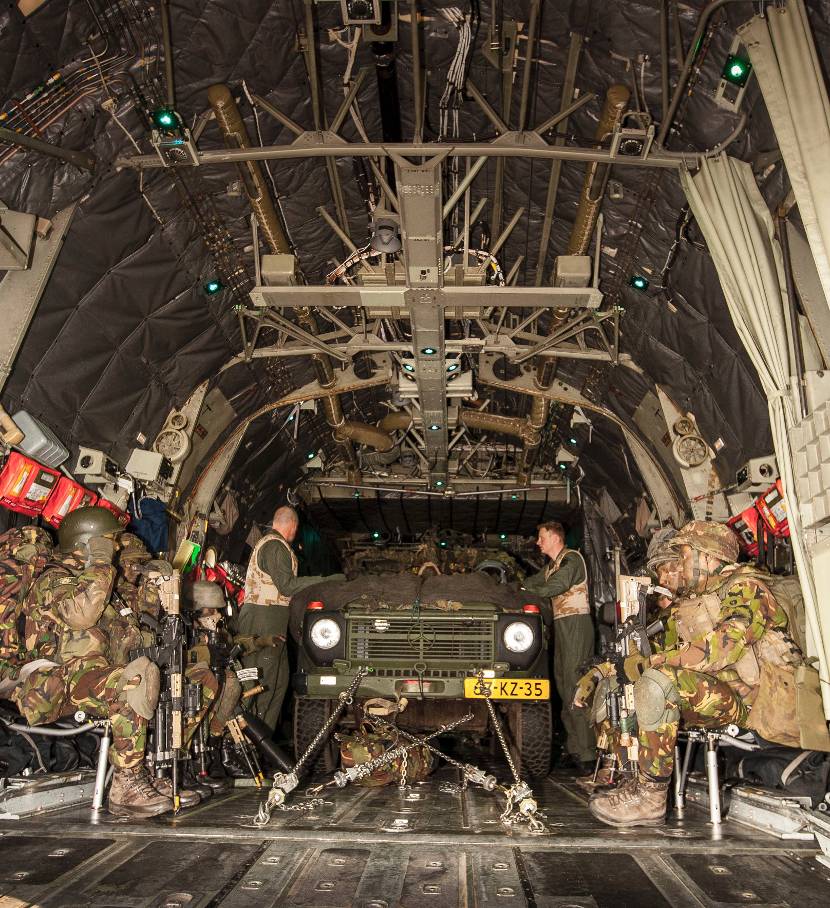 Een groep militairen met een militair voertuig in een C-130 Hercules-transportvliegtuig.