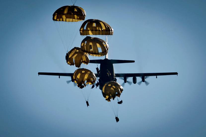 Parachutisten springen uit een C-130 Hercules.
