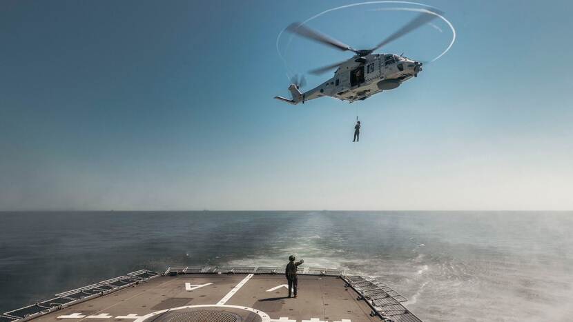 Helikopter boven het landingsplatform van een schip.