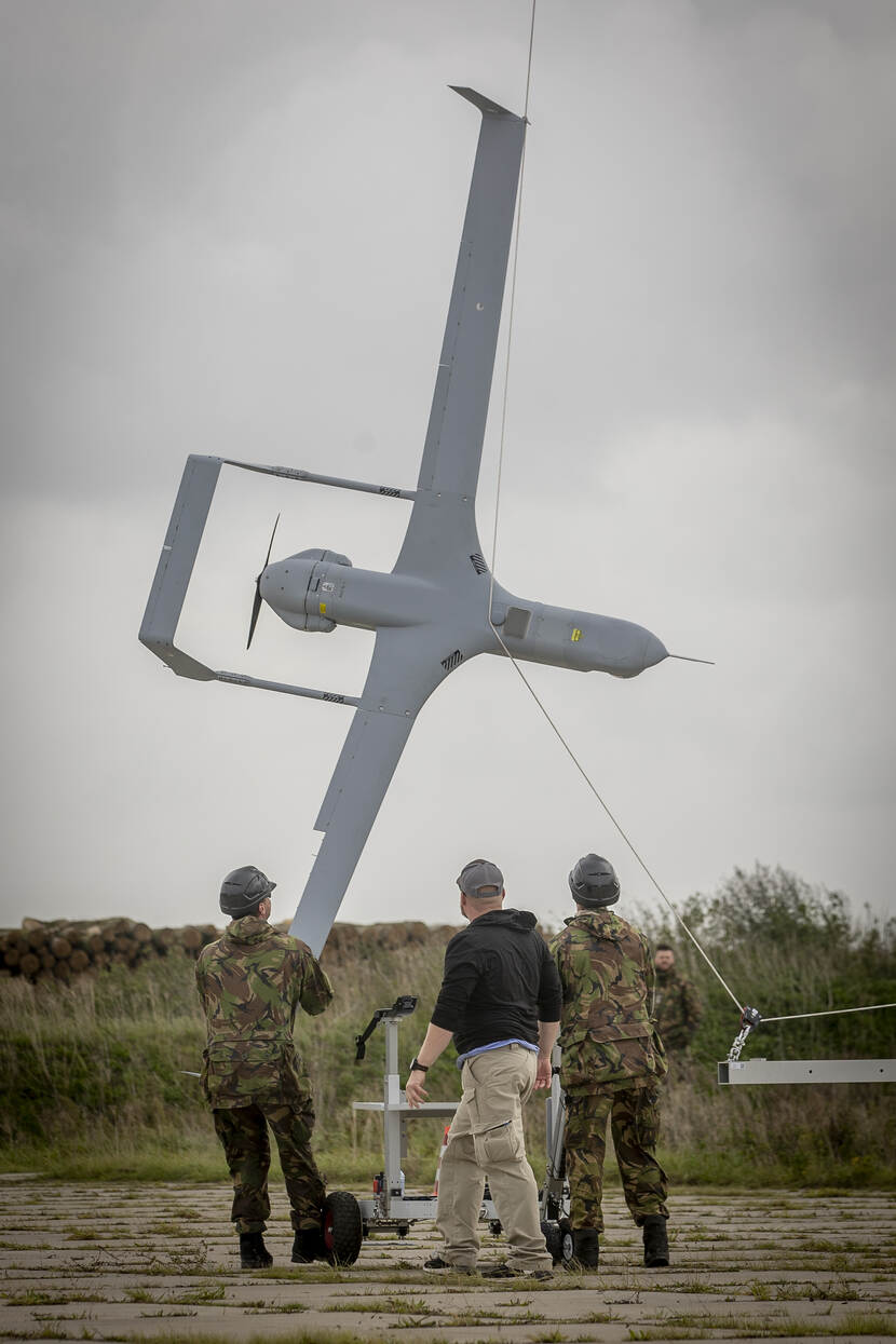 3 personen halen een onbemand toestel met een opvanginstallatie uit de lucht.