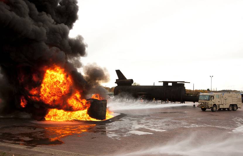 Bandweerwagen blust een vliegtuigbrand.