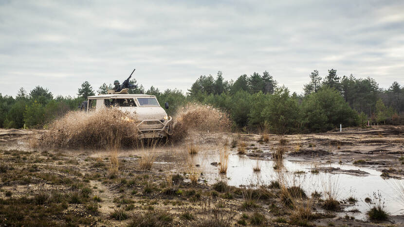 Anaconda-terreinwagen rijdt door opspattend water op de heide.