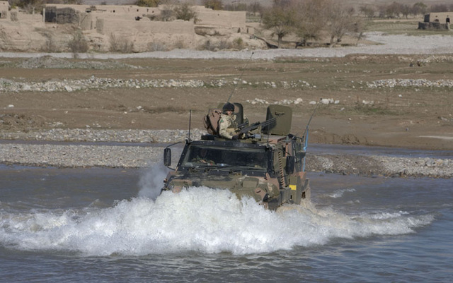 Bushmaster rijdt door het water.