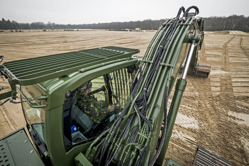 Een rupsgraafmachine maakt de grond plat.