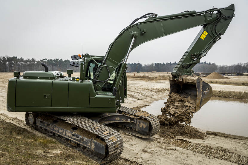 Een rupsgraafmachine schept zand.