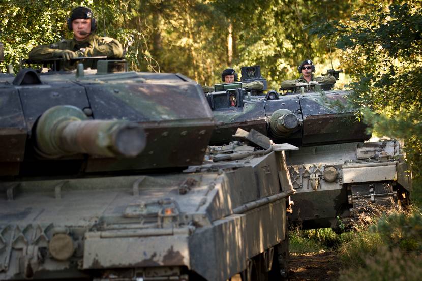 2 tanques de batalha do leopardo dirigem um após o outro em uma floresta.