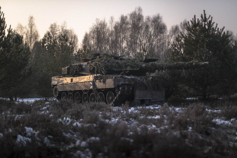 Een gecamoufleerde gevechtstank rijdt door besneeuwd terrein.