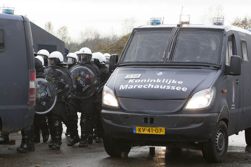 Een Mercedes-Benz Sprinter. Daarnaast staan leden van een bijstandseenheid.