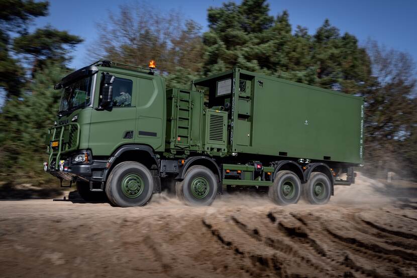 De 8-wielaangedreven (4-assig) high operational rijdt door de modder in het bos.