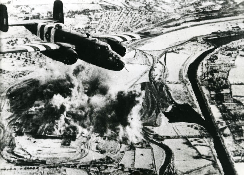 Een B-25 Mitchell vliegtuig gooit zijn bommen boven Caen (Frankrijk).