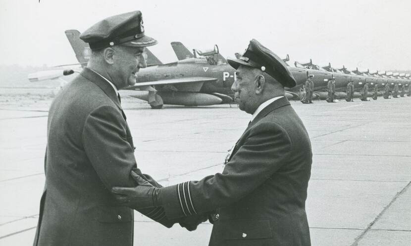 Zwart-wit foto van 2 militairen die elkaar een hand geven.