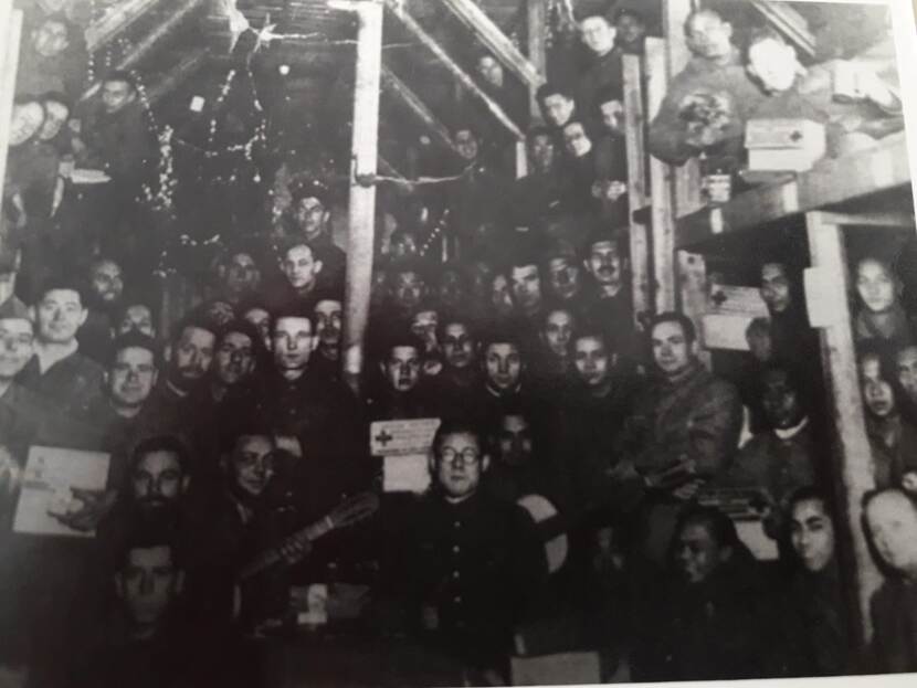 Een groep krijgsgevangenen in Japan, met kerstboom en Rode Kruisvoedselpakketten (zwart-wit foto).