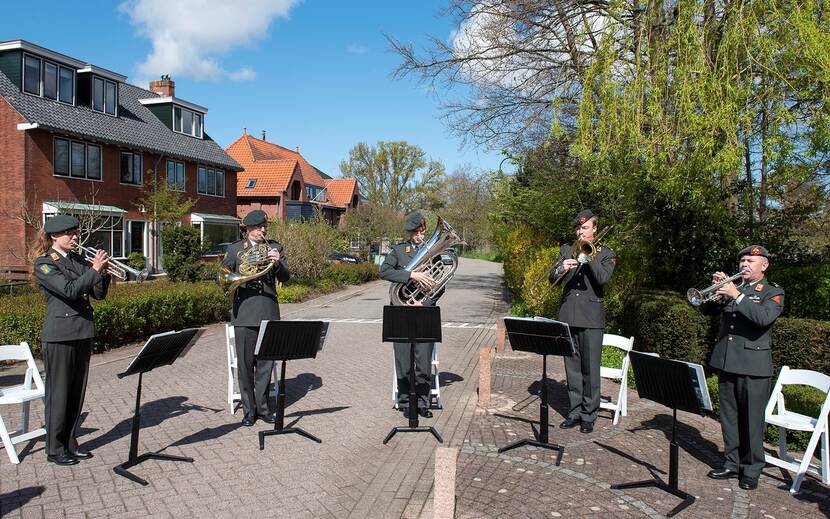 Koperkwintet posteert buiten met muziekinstrumenten.