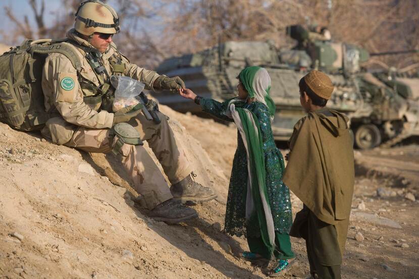 Militair deelt tijdens een patrouille snoep uit aan Afghaanse kinderen.