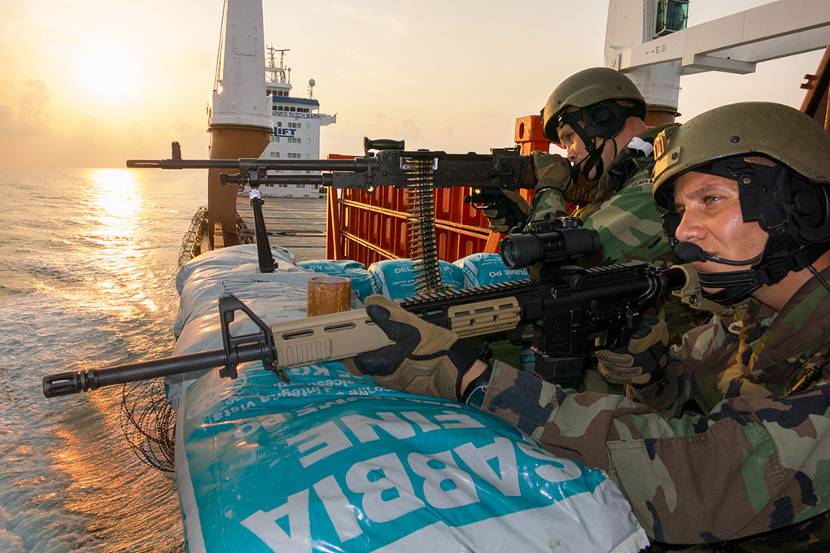 Militairen met wapens aan boord van marineschip.