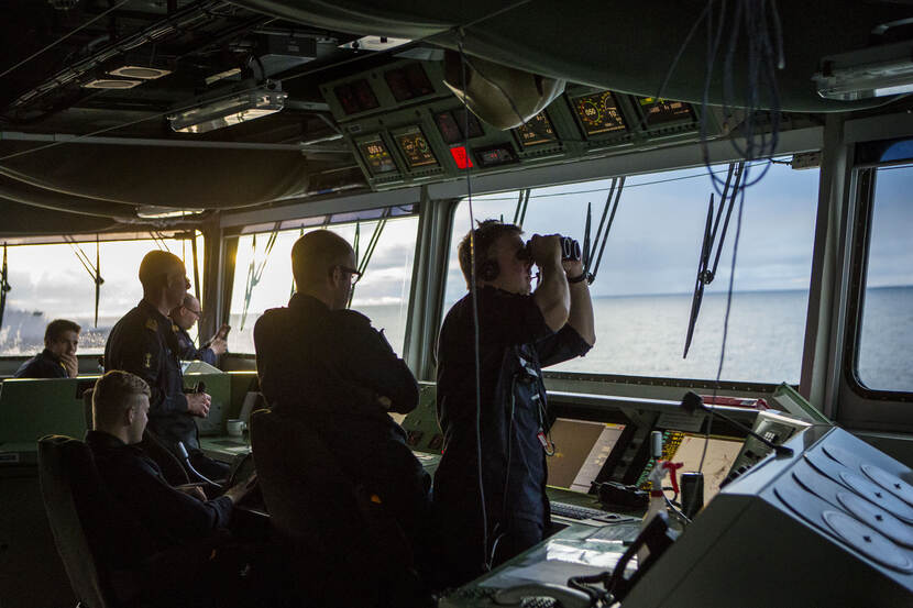 Militairen kijken vanaf de brug van de De Ruyter.