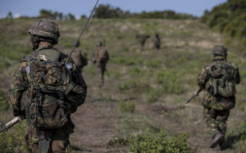 Militairen lopen door groen gebied.