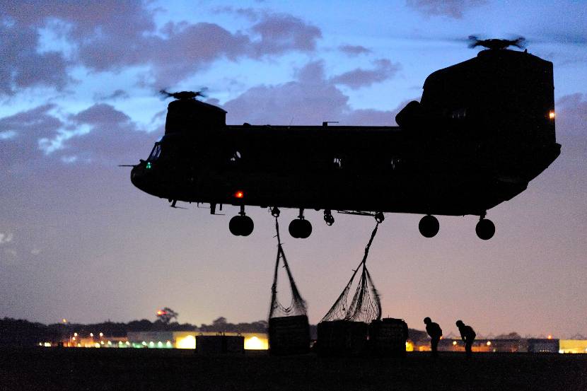 Een Chinook-transporthelikopter vervoert tijdens een nachtvlucht goederen.