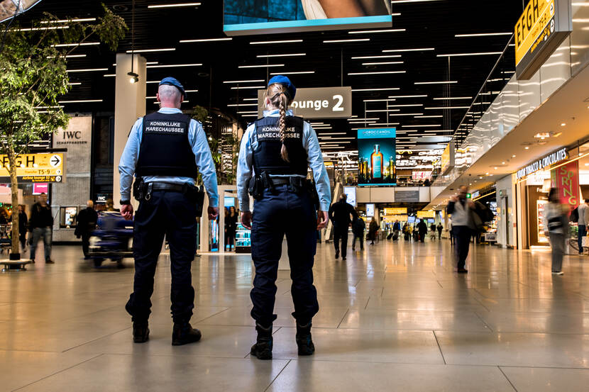 Een mannelijke en vrouwelijke marechaussee, op de rug gezien.