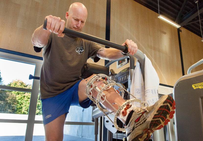 Een man traint zijn been met behulp van een speciaal apparaat.