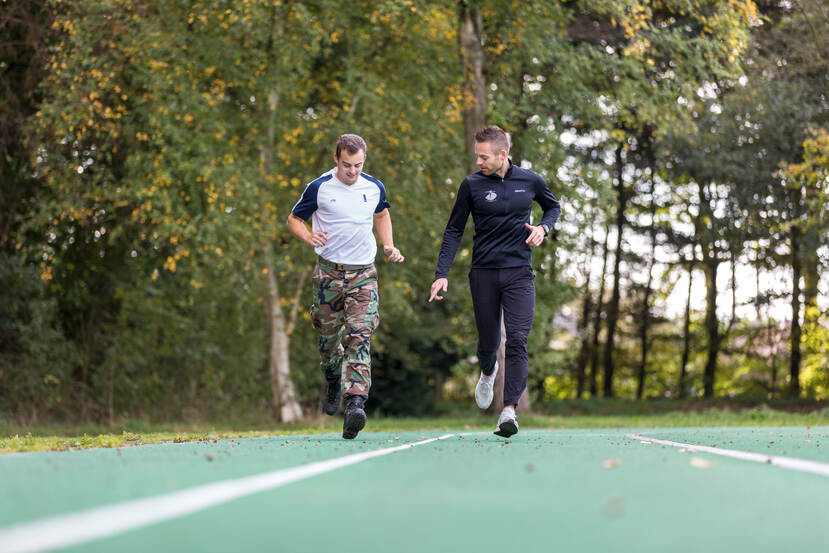 2 mannen lopen op een groene atletiekbaan.