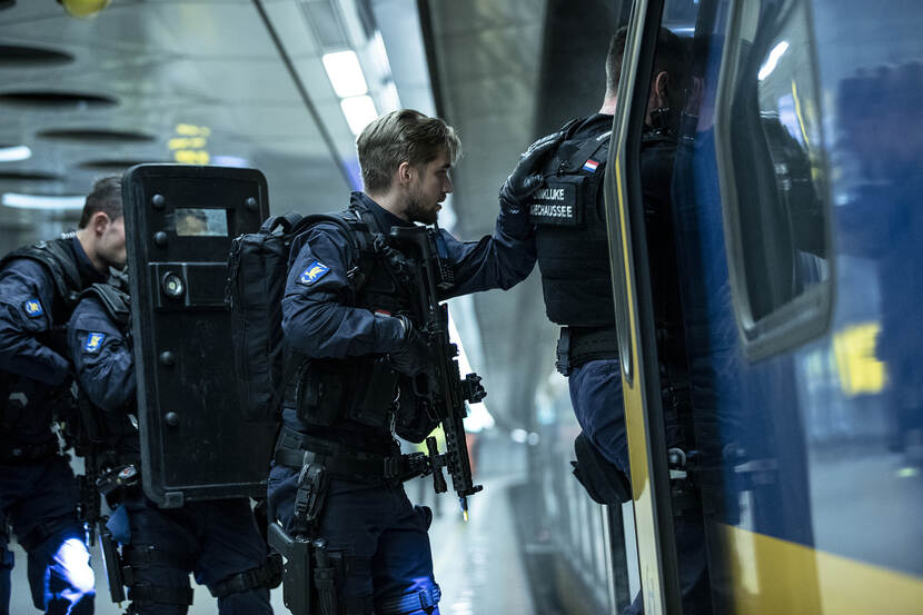 Marechaussees lopen achter elkaar een trein in.