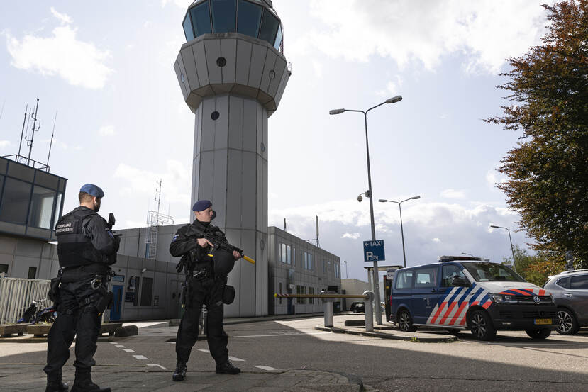 2 marechaussees staan voor de ingang van een luchthaven.